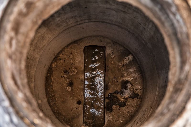 Inside a rusty circular pipe, a dirty metal plate blocks the center opening.