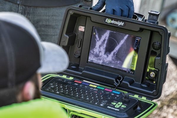 Inspector using a rugged handheld device to view a pipe inspection scan outdoors