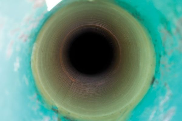 Close-up of a dark circular tunnel or drain with greenish-blue surrounding edges