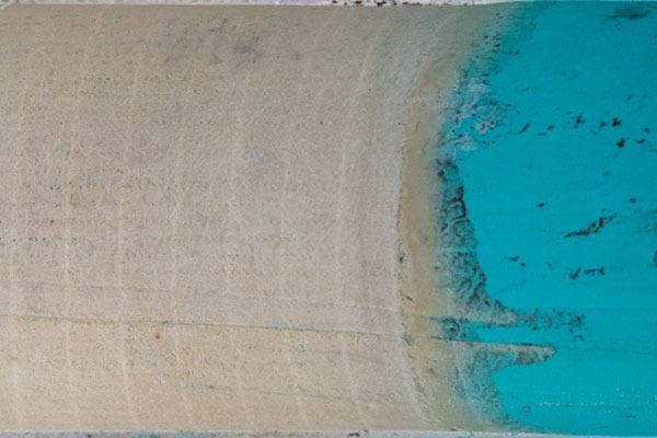 Close-up of a beige wooden surface beside bright turquoise water