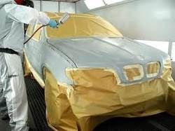 A man is spray painting a car in a paint booth.