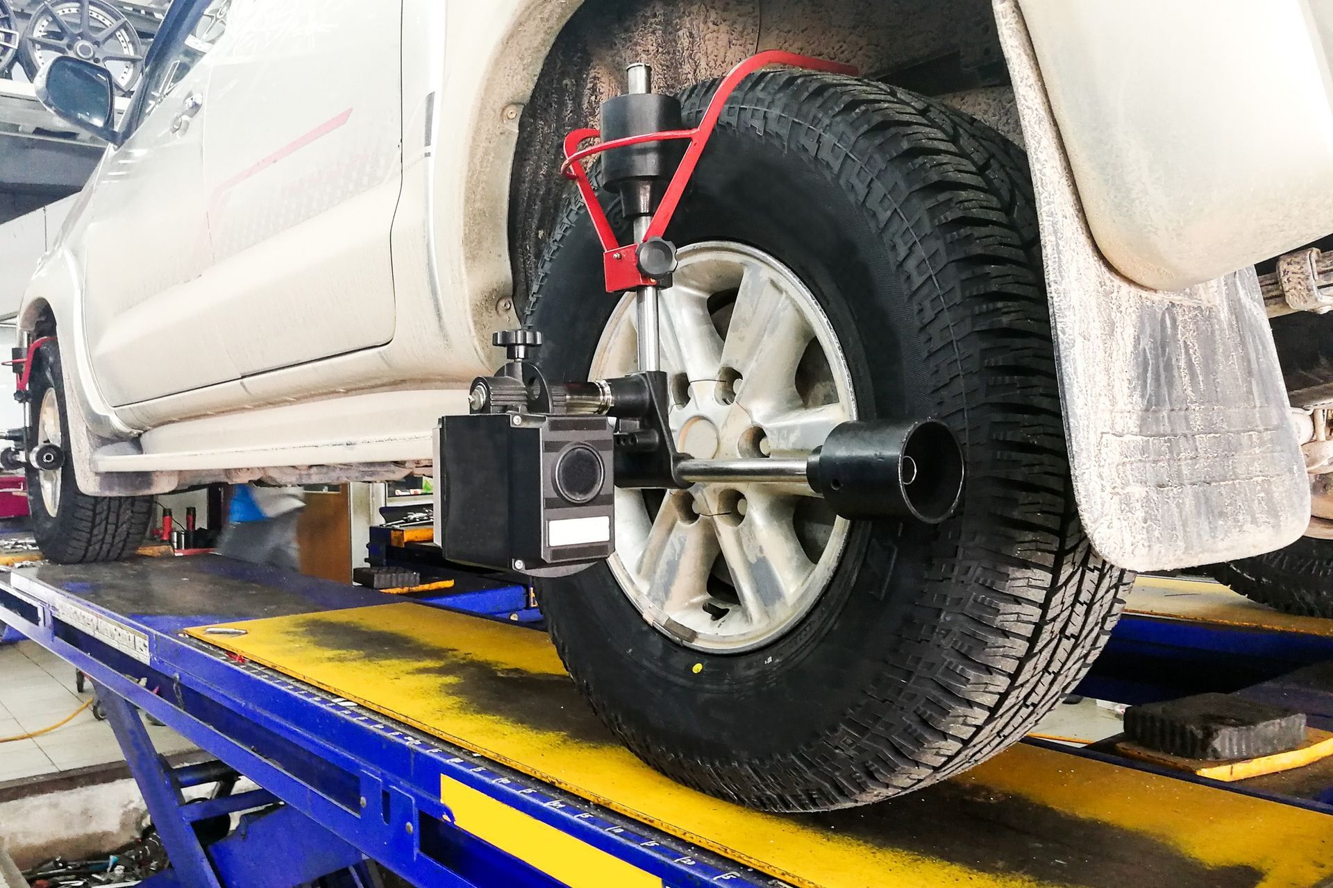 A white truck is being aligned on a lift in a garage.