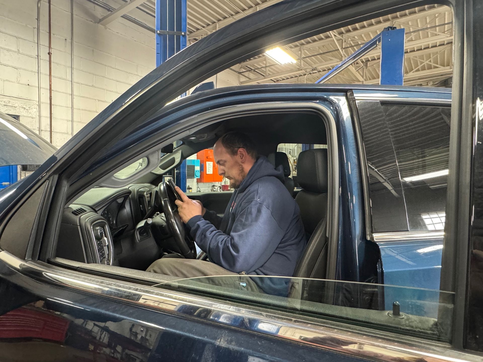 A man is sitting in a car looking at his phone.