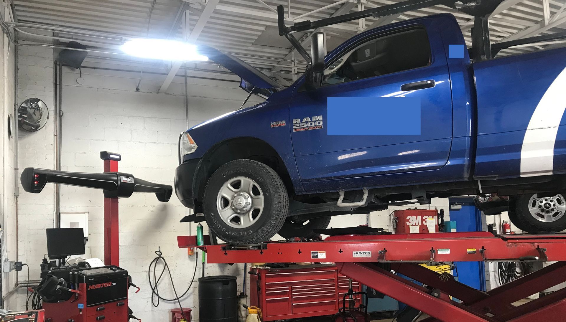 A blue truck is sitting on top of a red lift in a garage.