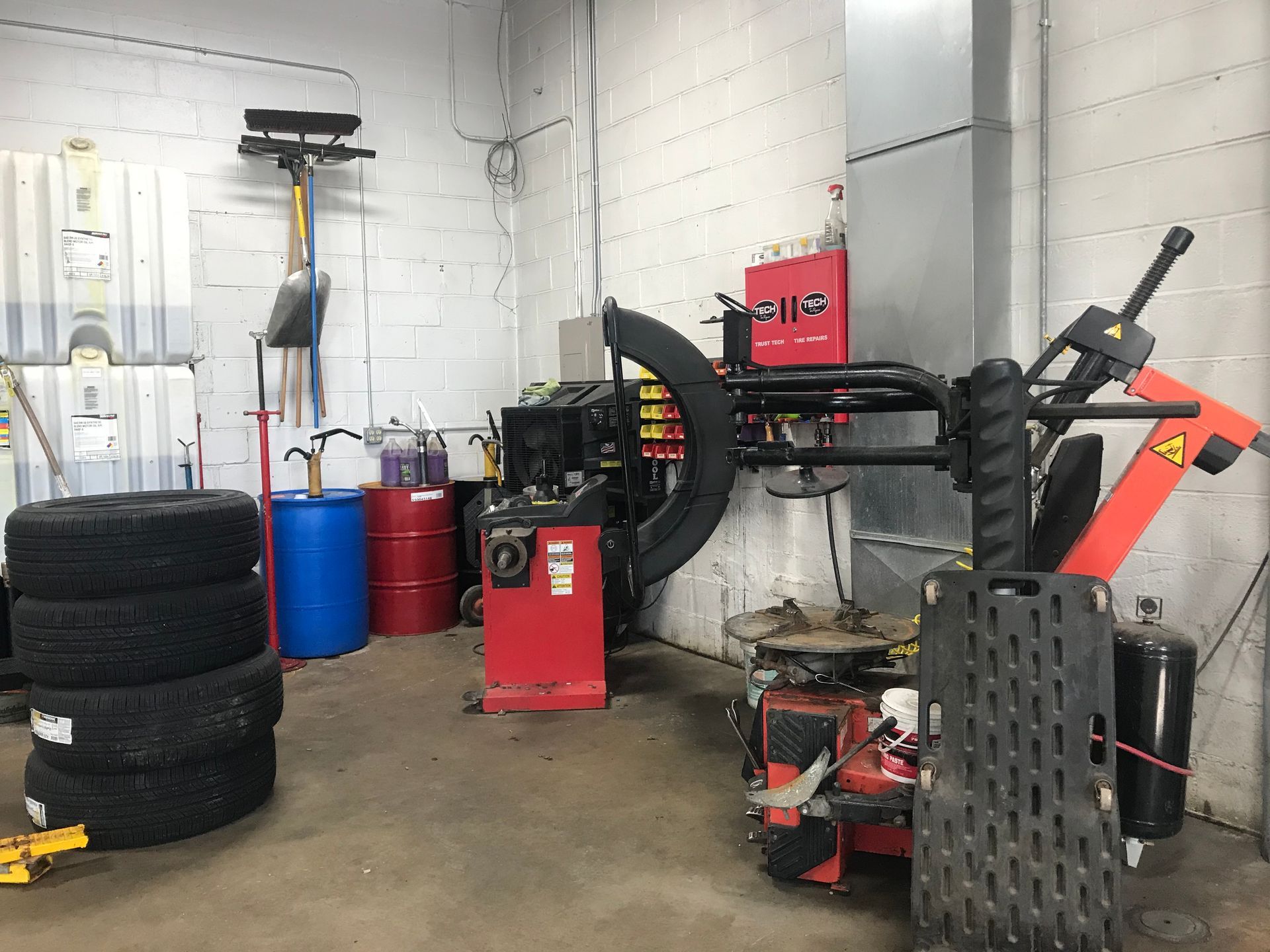 A tire changer is sitting in a garage next to a stack of tires.