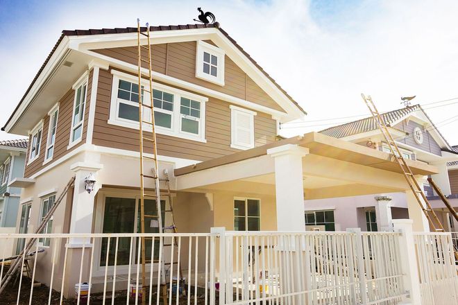Two-story house with white trim, brick siding, and a covered porch behind a white fence