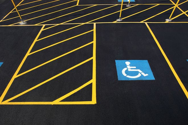 Accessible parking space with blue wheelchair symbol and yellow hatch markings on black pavement