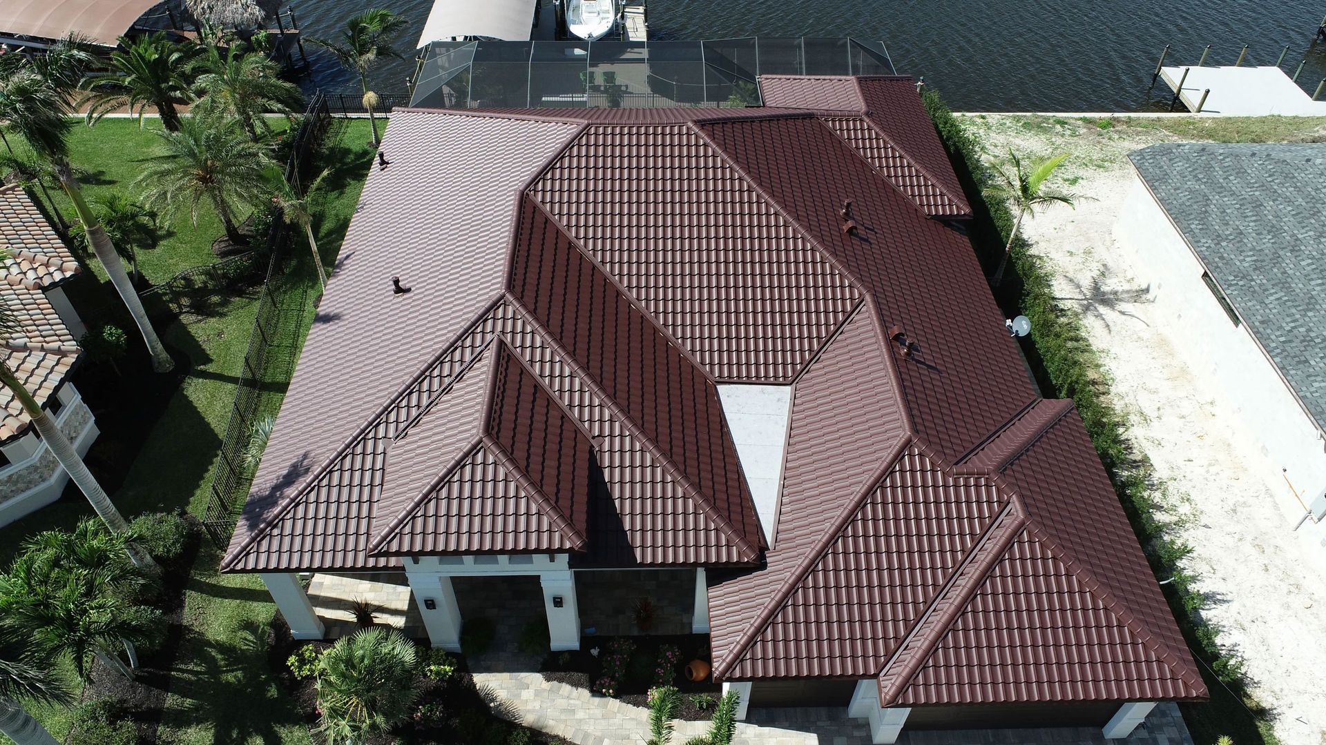 Aerial view of a house with a brown tiled roof and surrounding trees