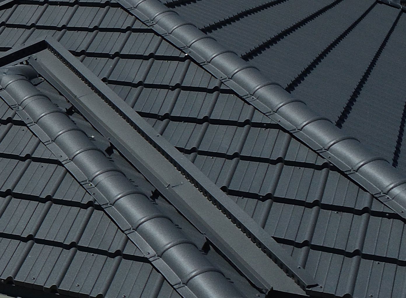 Dark gray metal roof with overlapping tiles and ridges