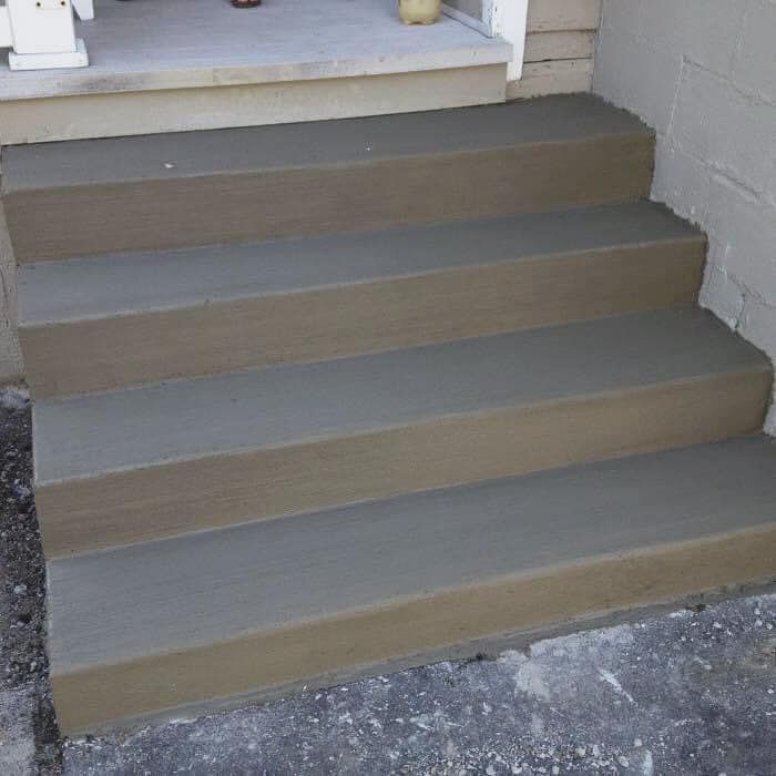 A set of concrete steps leading up to a porch.