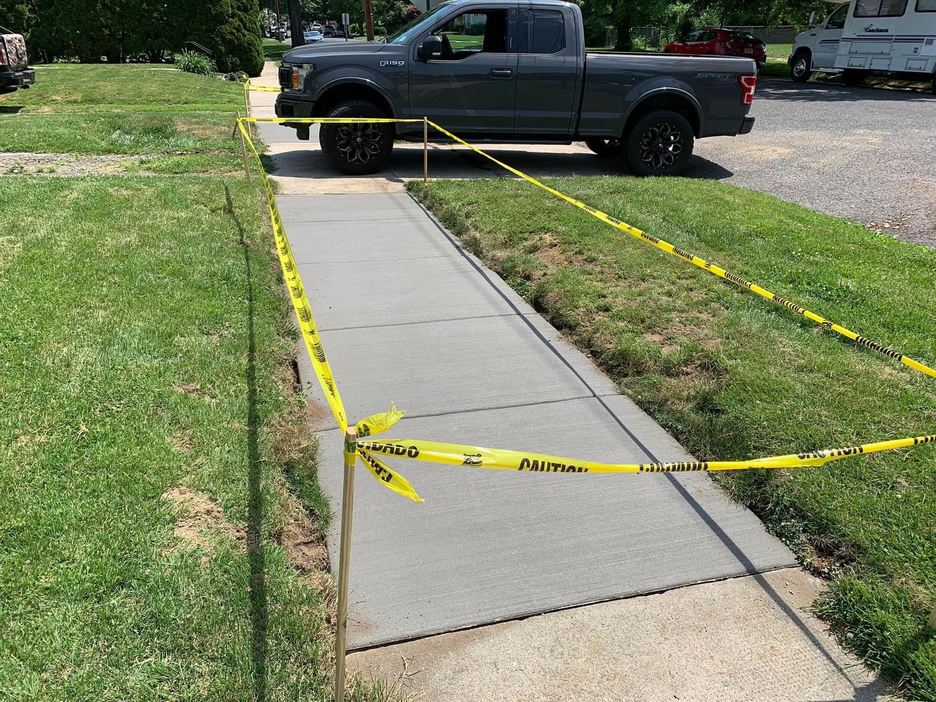 A gray truck is parked on a sidewalk surrounded by yellow tape