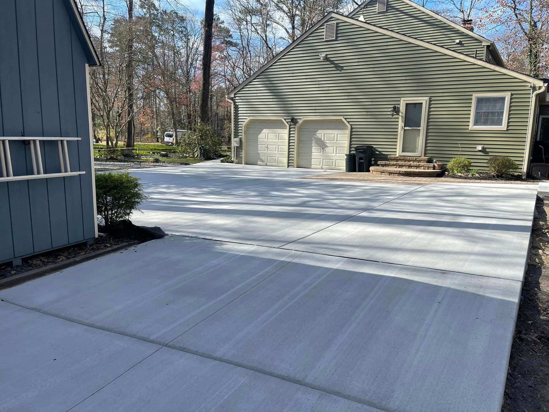 A concrete driveway leading to a house with two garage doors
