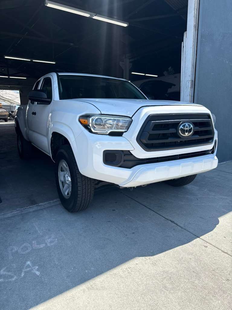 White Toyota Tacoma pickup parked in a garage, front three-quarter view