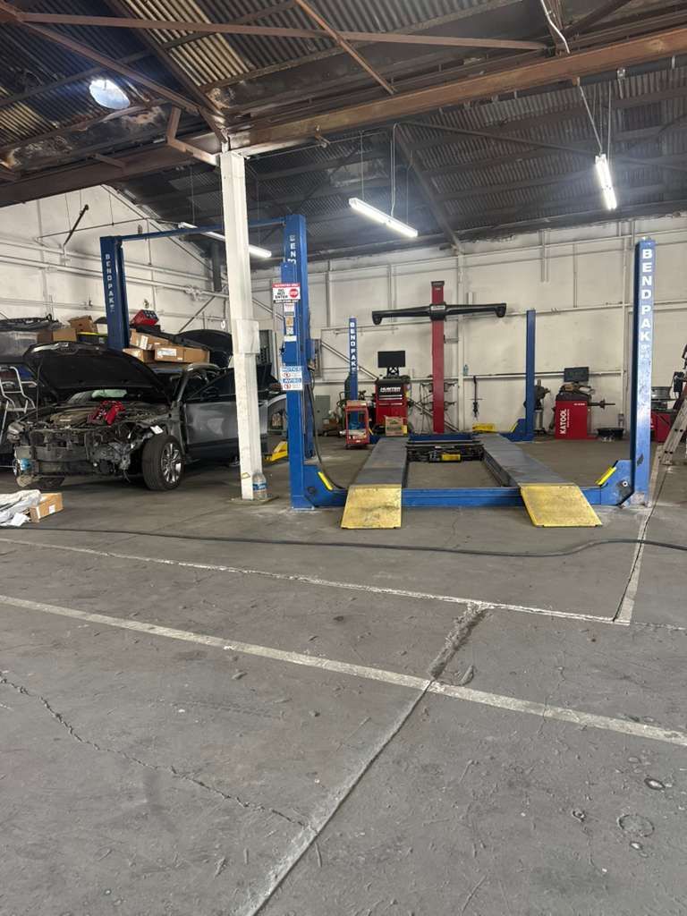 Auto repair garage with a car on a lift and blue-and-yellow ramps inside a workshop