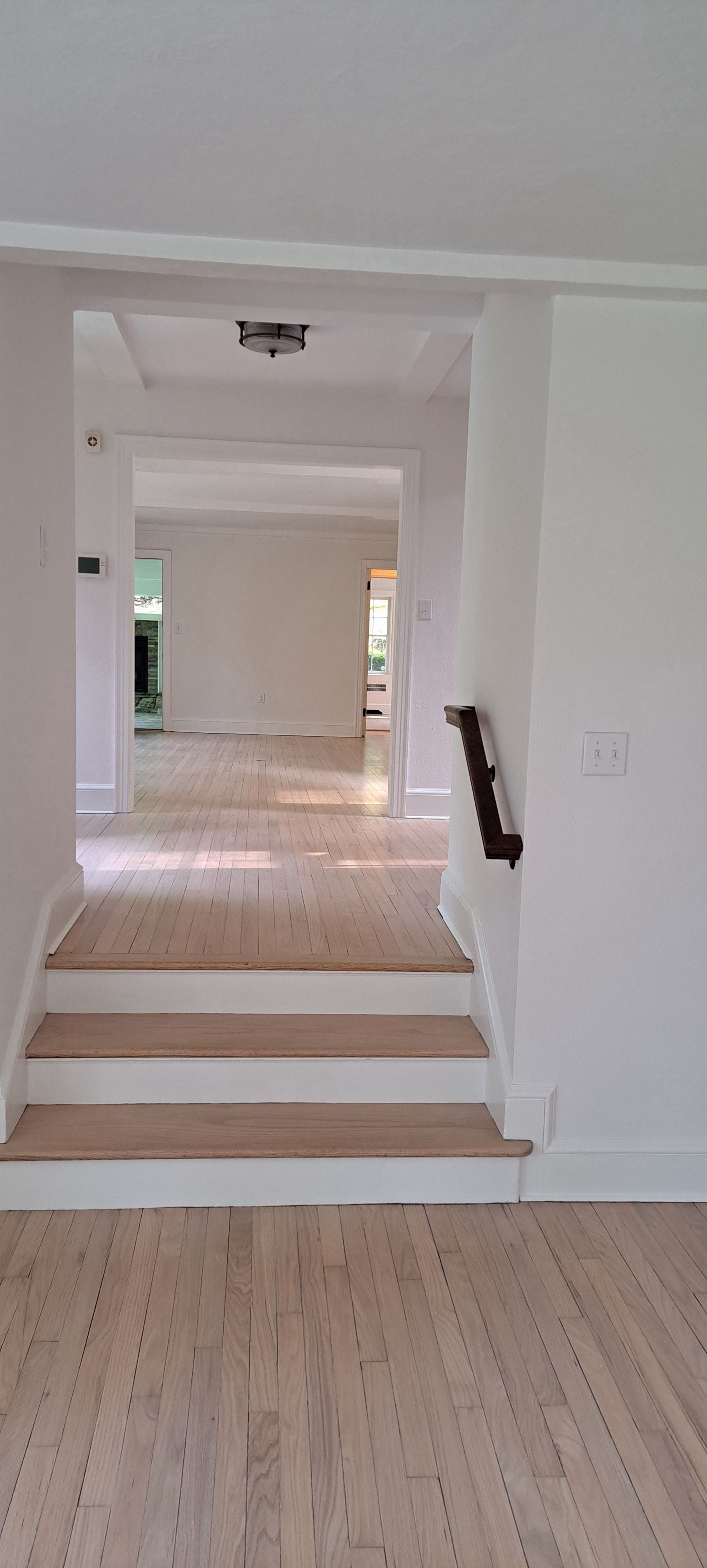 Bright hallway with steps leading to a white interior room and doorway.