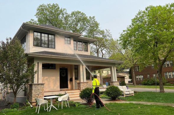 A man is spraying water on the roof of a house.