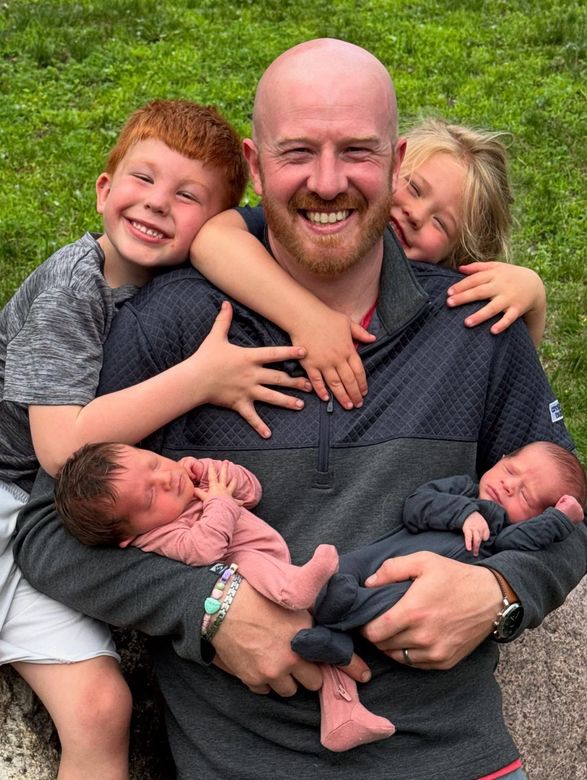 A man is holding three babies and three children.