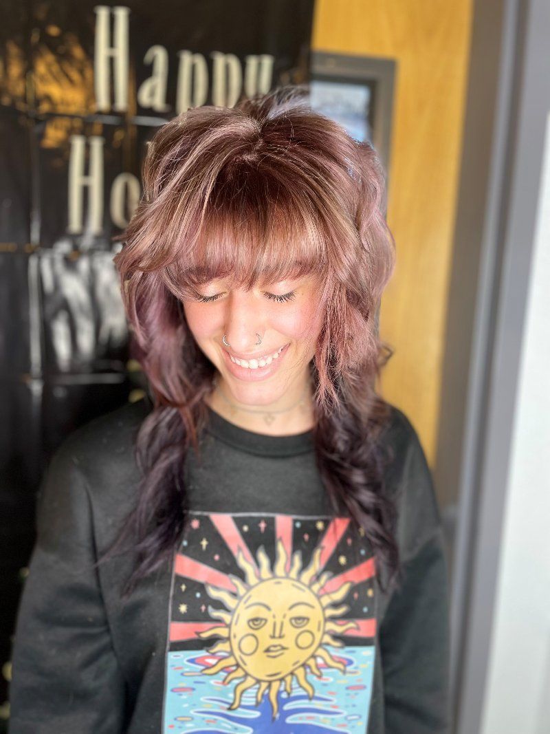 A woman wearing a black shirt with a sun on it is smiling.