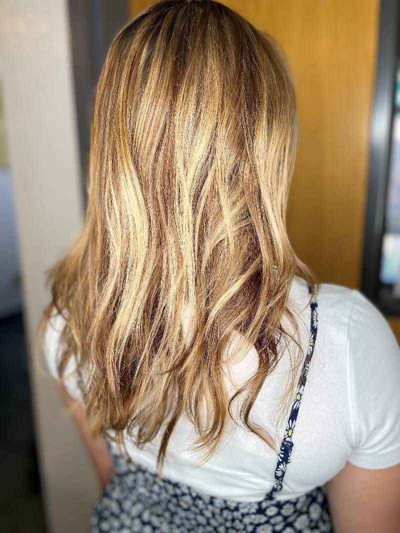 A woman with long blonde hair is wearing a white shirt and a leopard print skirt.