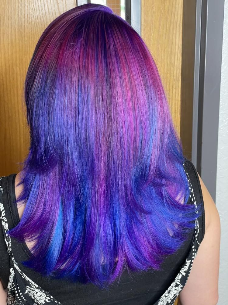 A woman with purple and blue hair is wearing a black tank top.
