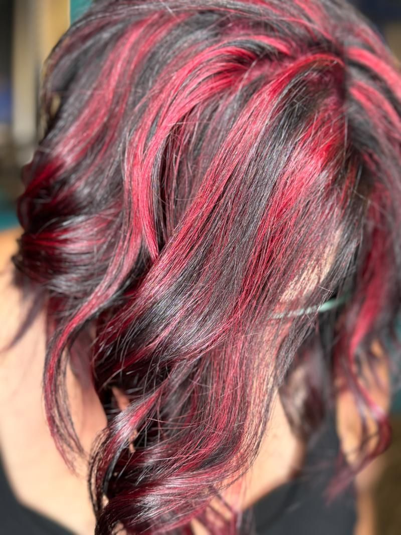 A close up of a woman's hair with red highlights.