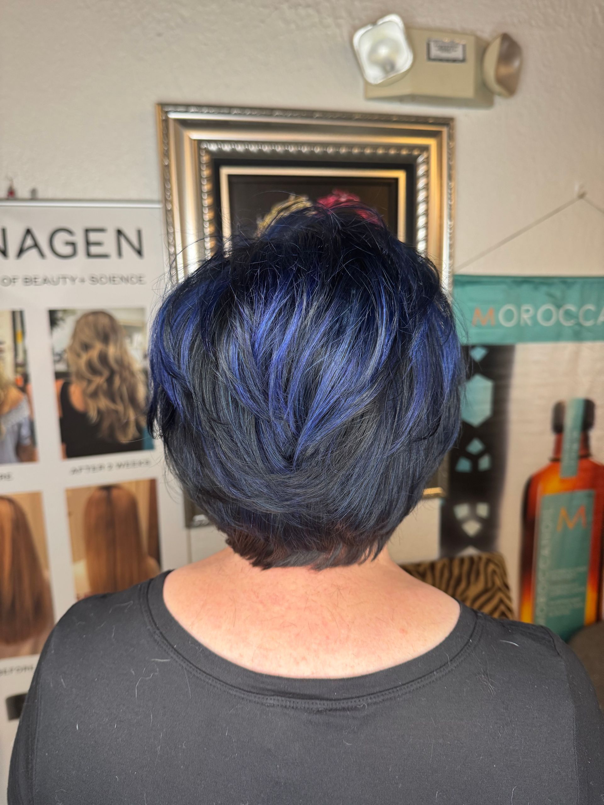 A woman with blue hair is wearing a black shirt