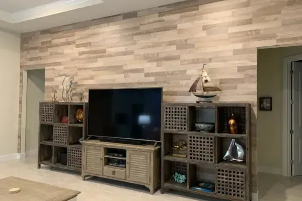 A TV console sits against a wood-paneled wall, flanked by two square shelving units with a model boat on the right unit.