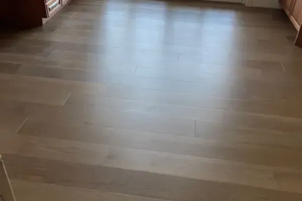 Light brown, wide-plank hardwood flooring with a smooth finish, viewed from a slightly elevated angle.