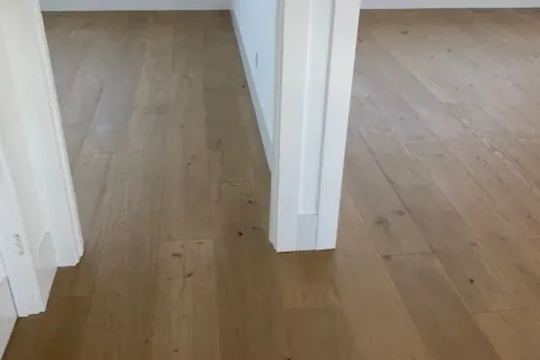 Light-colored wood flooring in a room with white walls and door frames.