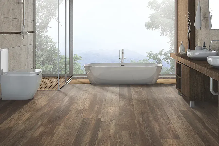 Modern bathroom featuring dark wood flooring, a white freestanding tub by a window, and a wall-mounted toilet.
