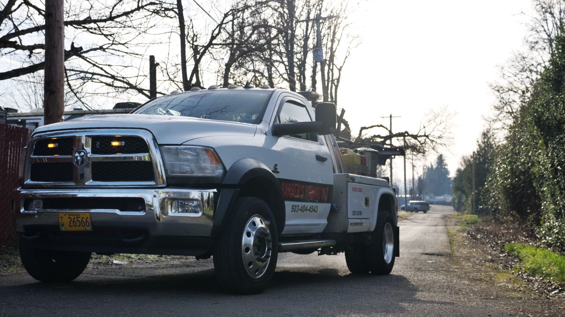 Tow truck on a road, front view. Gray truck with flashing amber lights; sunny day.