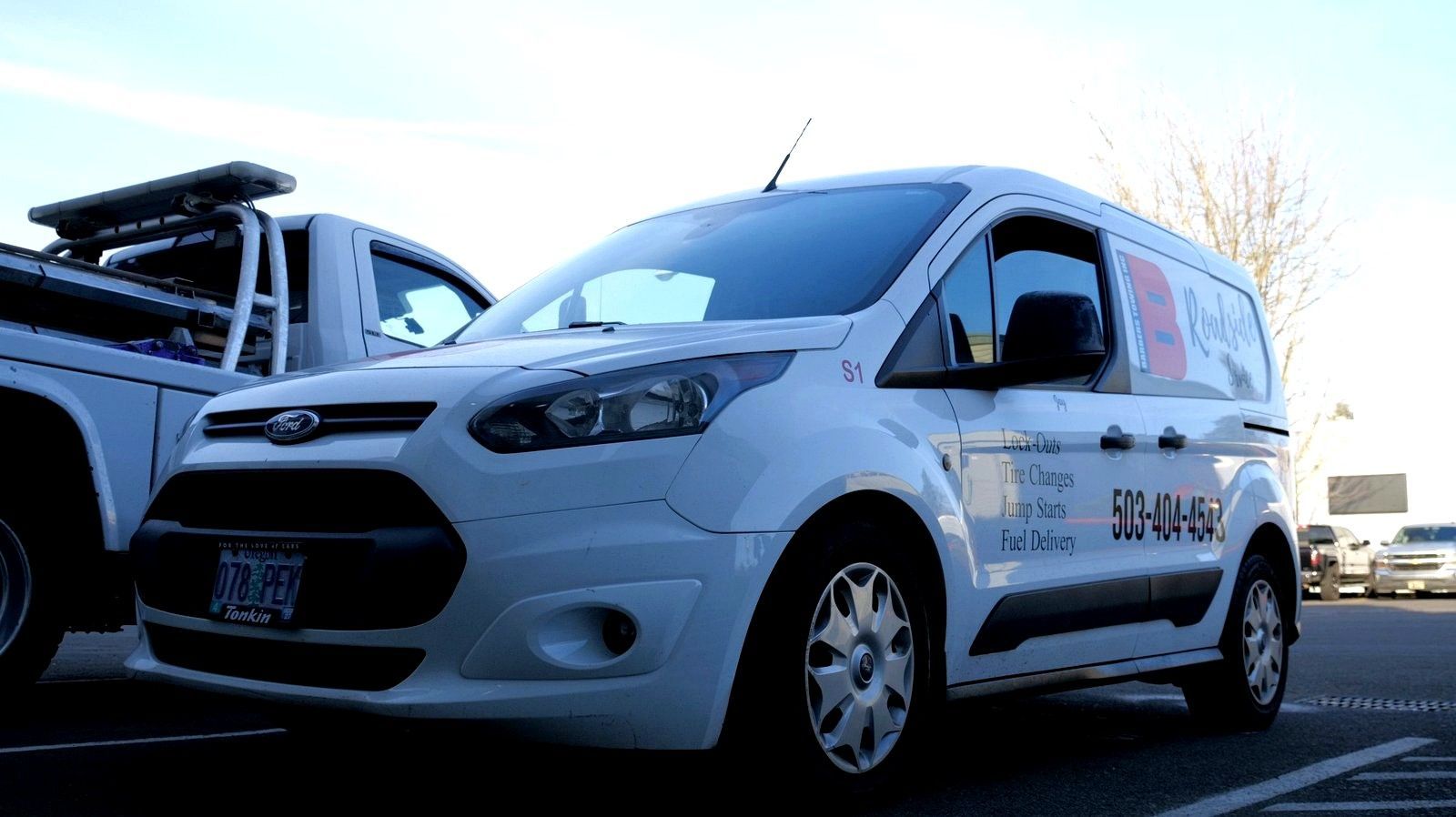 White Ford Transit Connect van parked, with company logo and phone number on the side.