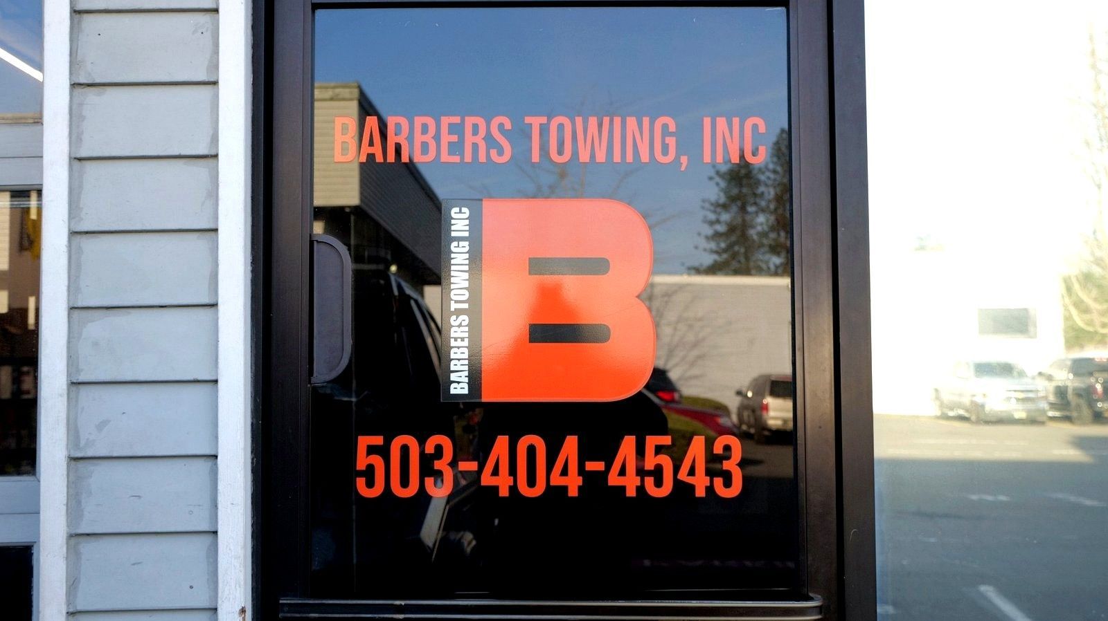 Barbers Towing, Inc. sign on a glass door: large orange 