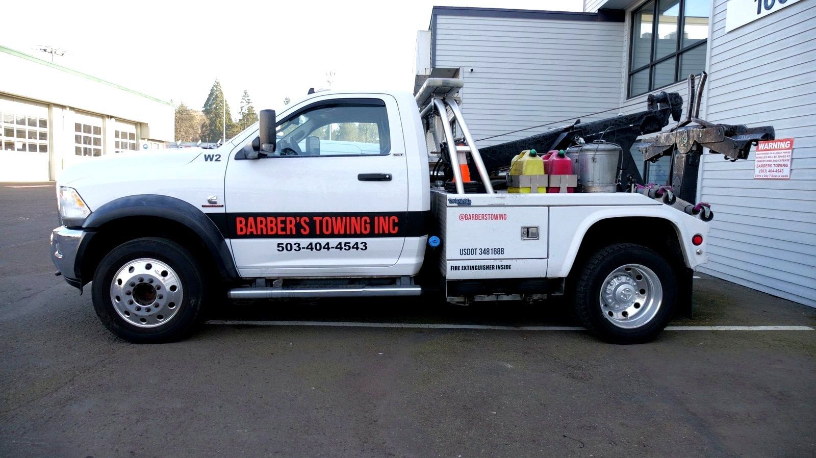 White tow truck parked in front of a building; company name Barber's Towing NC on the side.
