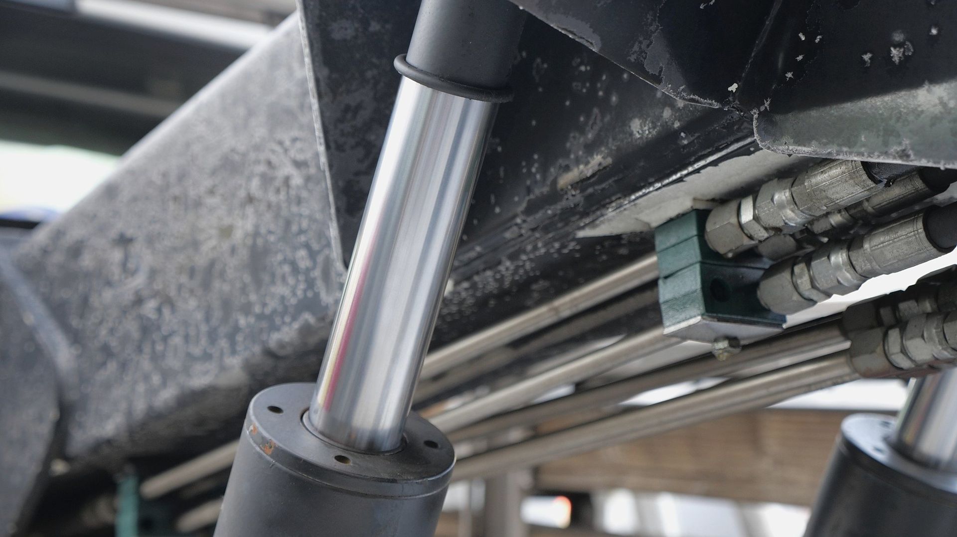 Close-up of hydraulic cylinders, tubing, and connections on a machine, likely a forklift or similar equipment.