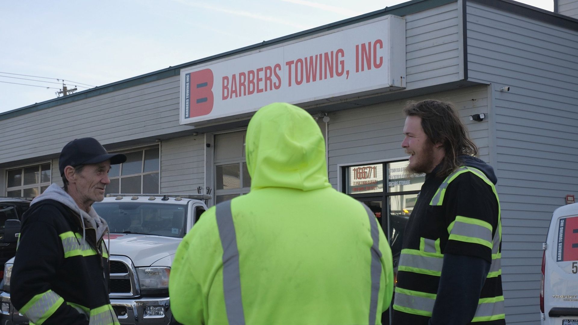 Three people standing outside Barber's Towing, Inc. building.