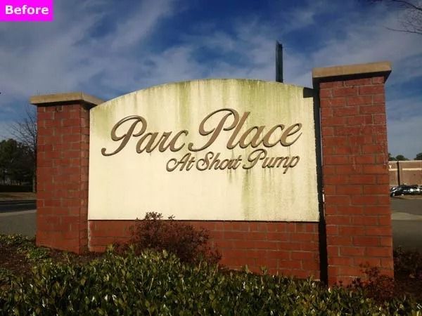 Brick entrance sign for Parc Place, with cream lettering and shrubs in front under a blue sky