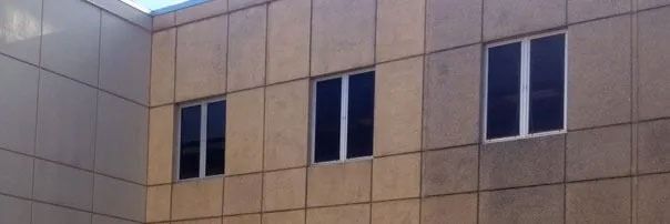 Tan building wall with four narrow windows under a blue sky