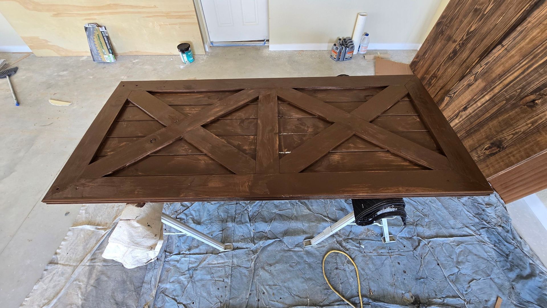 Wooden table top with brown cross design, on a work stand, near wood boards.