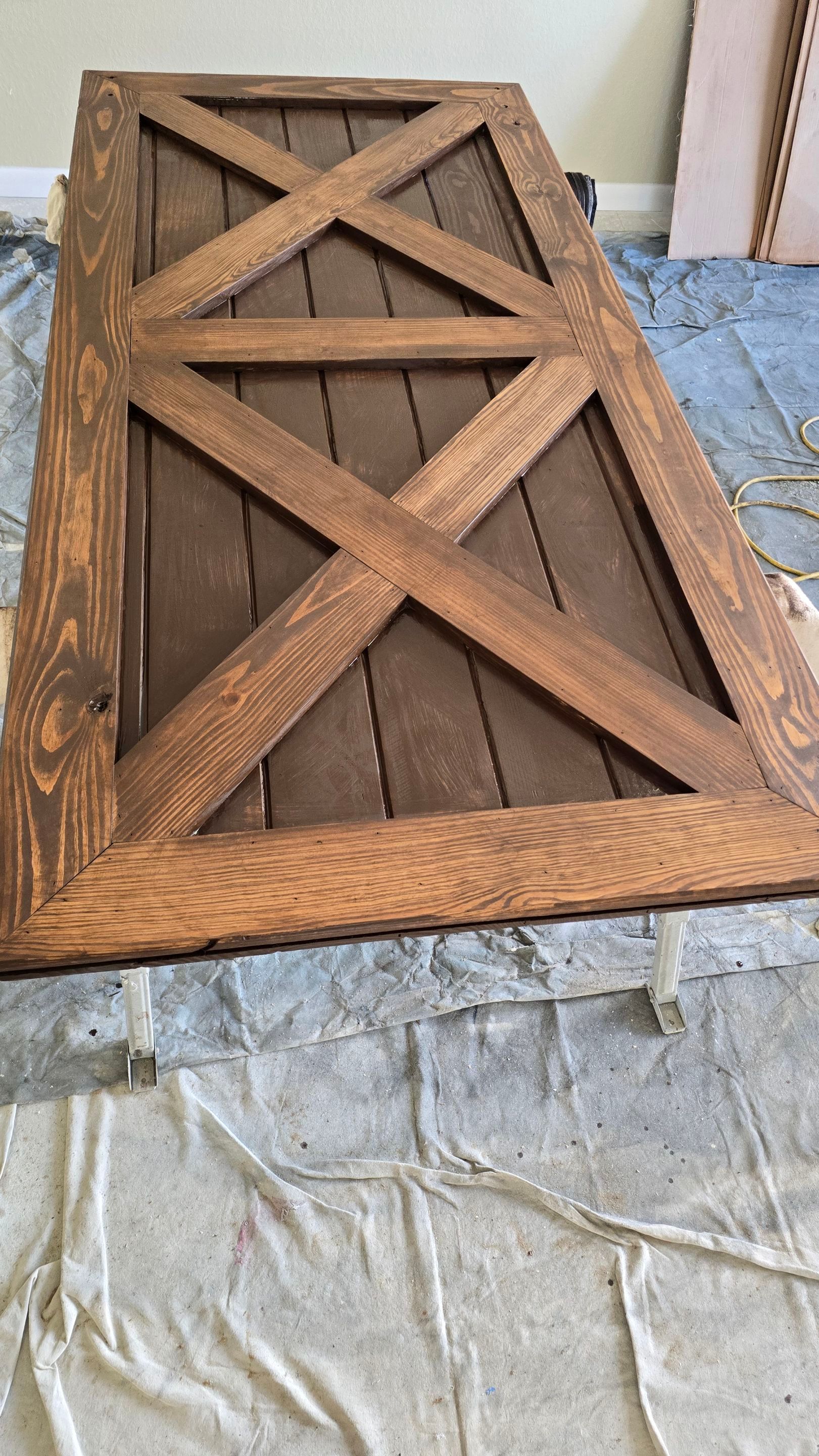 Wooden barn door with dark brown stained finish on a drop cloth.