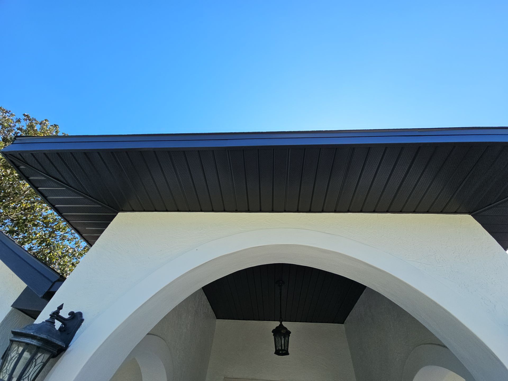 White arched entrance with black ceiling and blue sky.