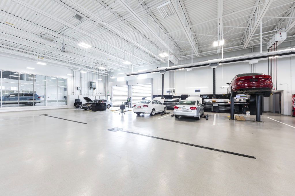 Bright auto service showroom with several cars under white ceiling lights