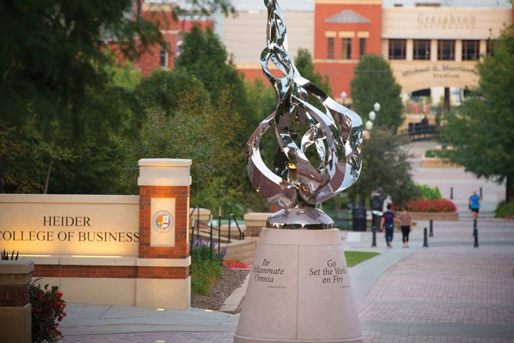 Campus walkway with a silver abstract sculpture and buildings in the background