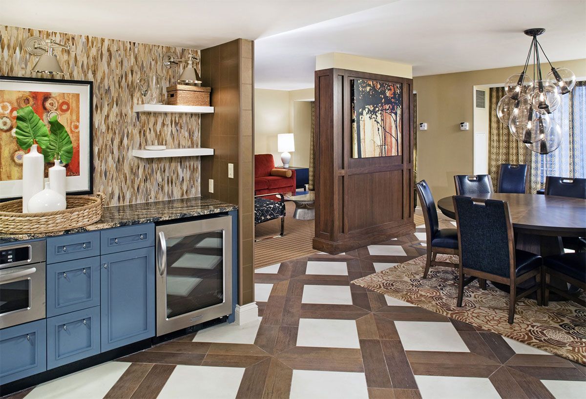 Open kitchen and dining area with blue cabinets, granite counters, wood floors, and patterned tile accents