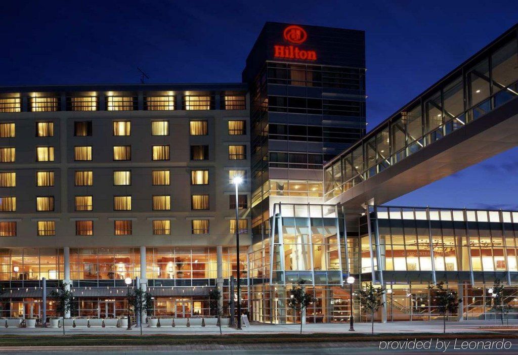 Nighttime view of a Hilton hotel with lit windows and a glass entrance canopy