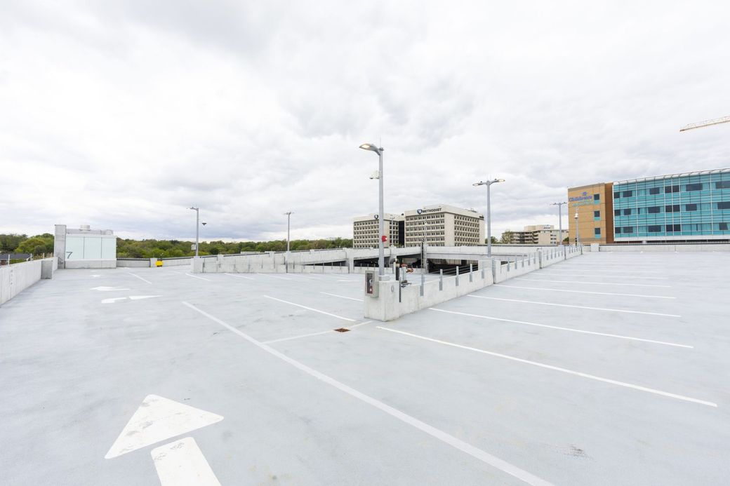 Empty rooftop parking lot with white lane markings and buildings in the distance