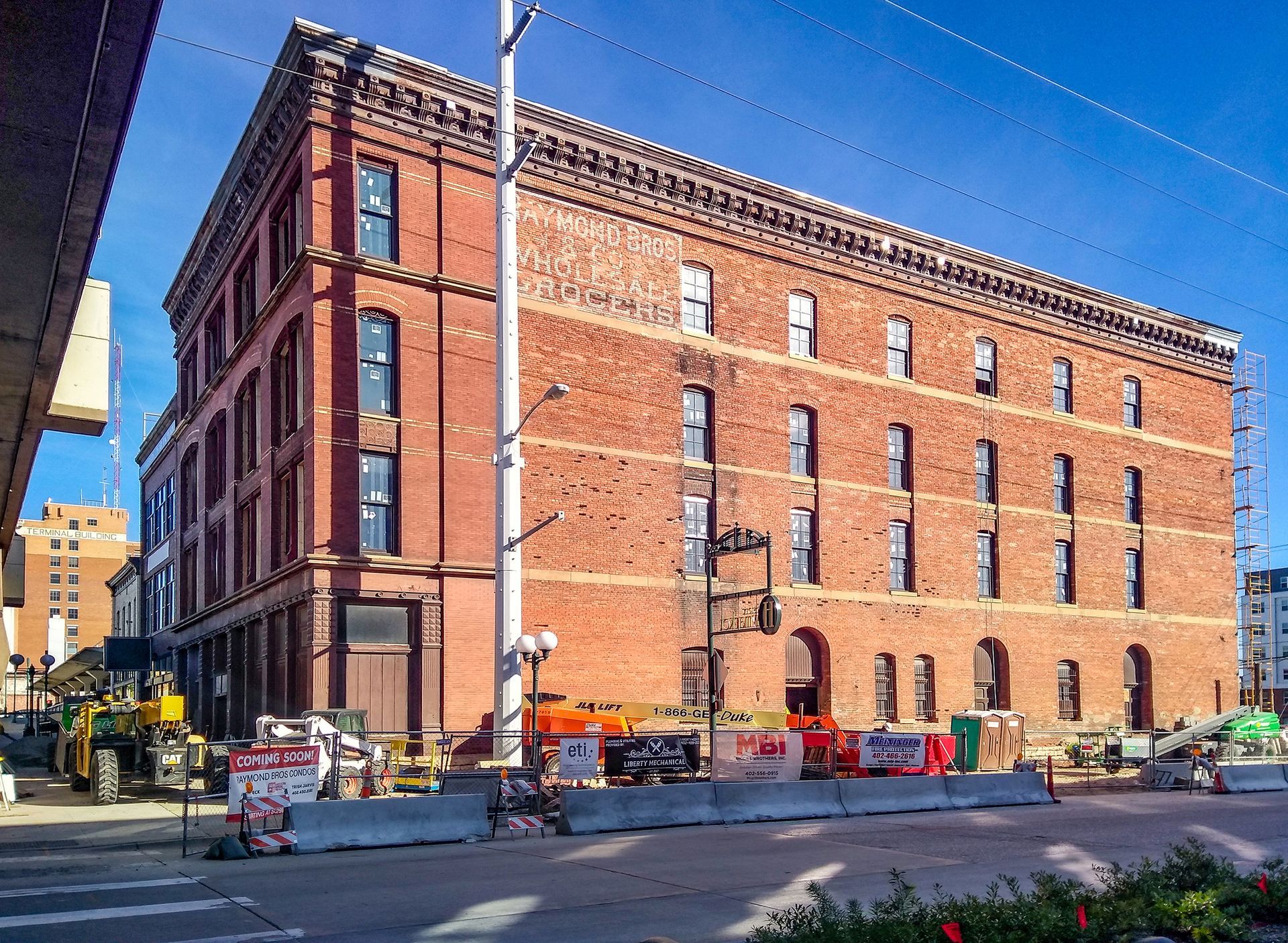 Large red-brick industrial building at a city street corner under a clear blue sky