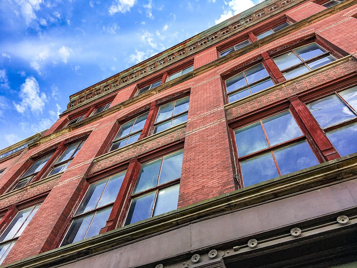Low-angle view of a red brick building with tall windows against a blue sky