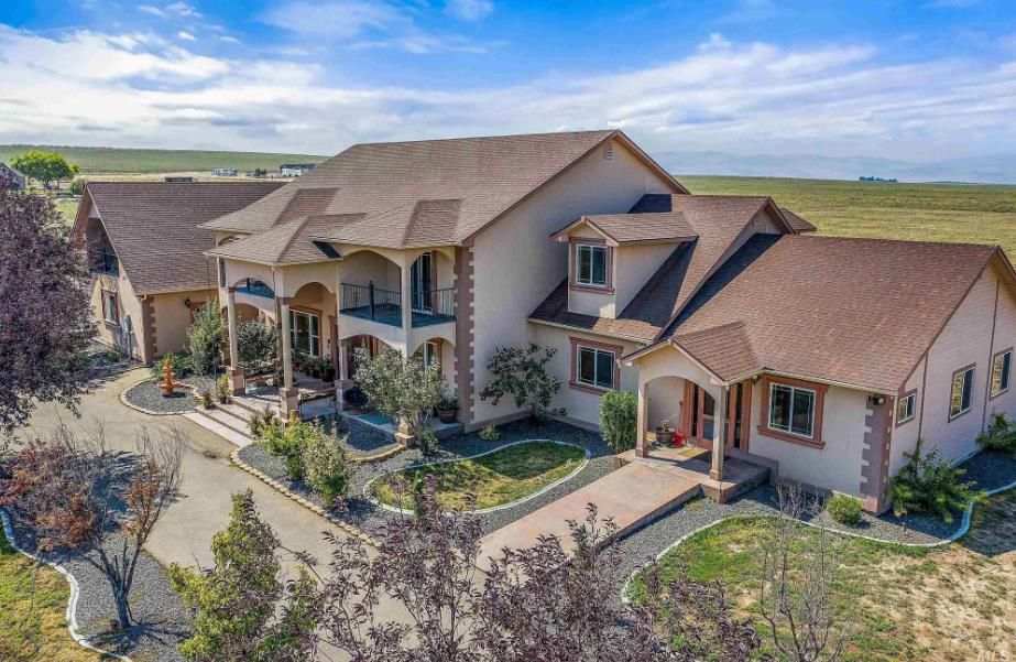 An aerial view of a large house in the middle of a field.