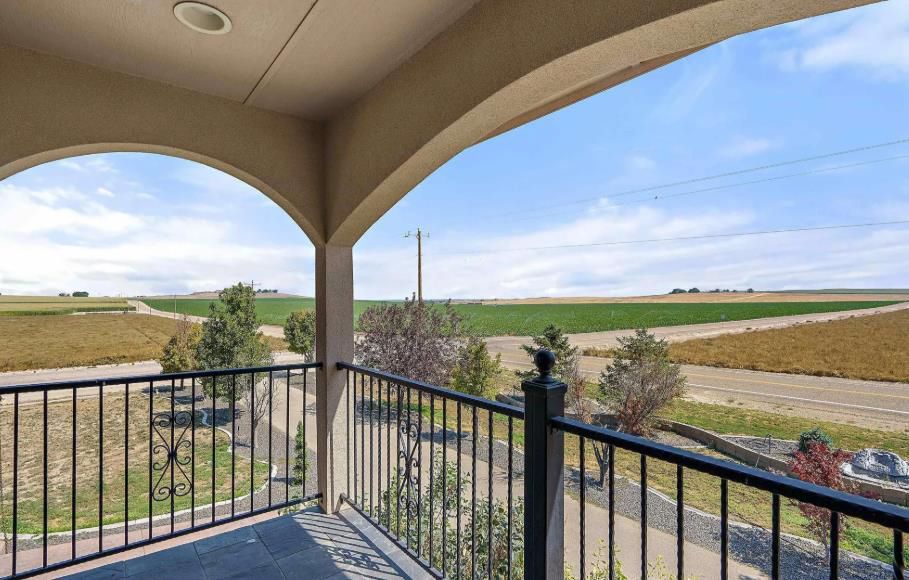 A balcony with a view of a field and a road.